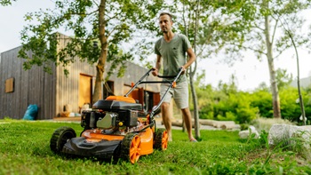 Un homme utilise sa tondeuse à gazon dans son jardin